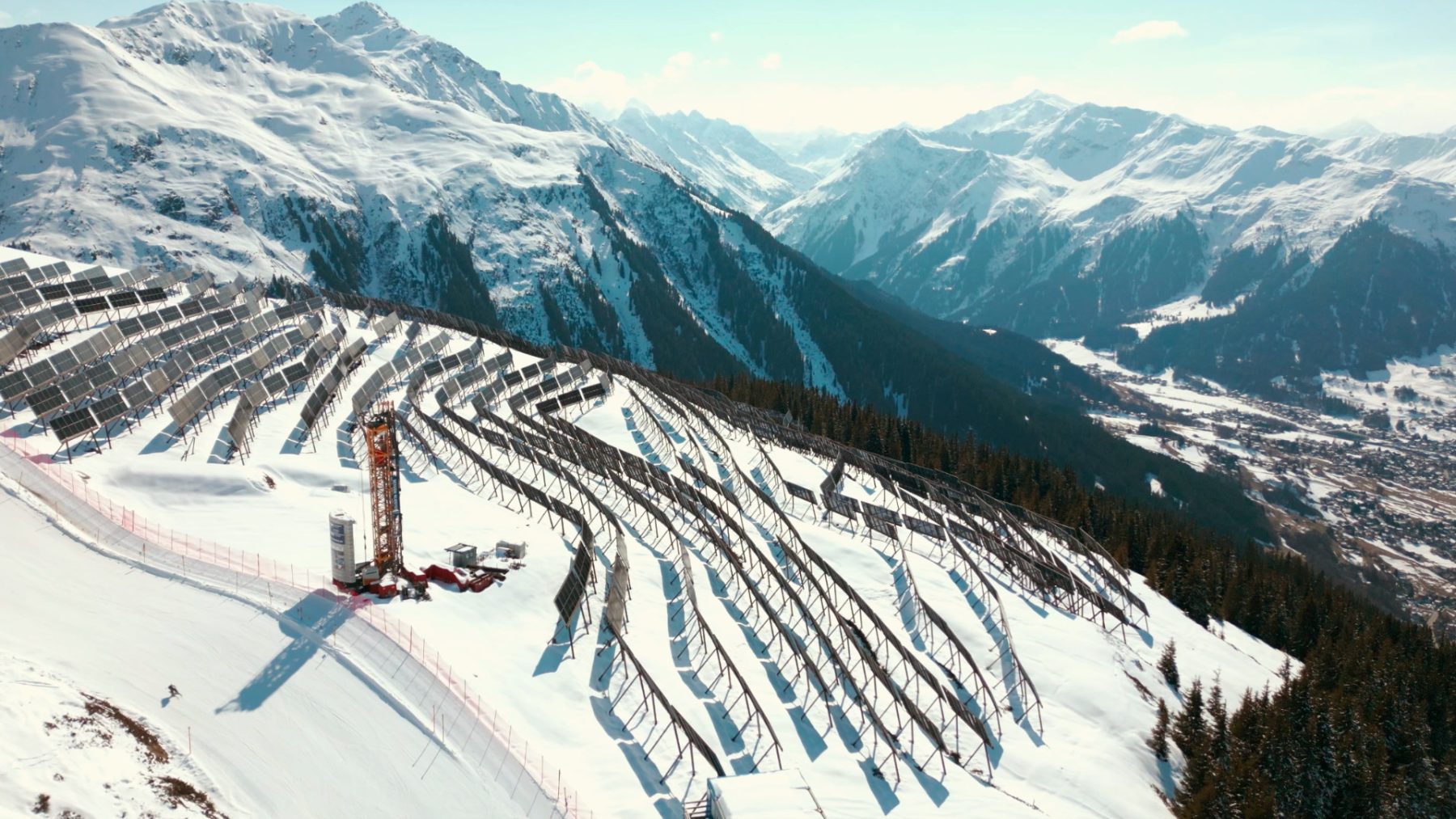 Luftaufnahme eines grossflächigen Photovoltaik-Feldes der Madrisa Solar AG auf einem schneebedeckten Berghang im Skigebiet Madrisa, Klosters. Im Hintergrund erstreckt sich eine weite Alpenlandschaft. Drohnenaufnahmen von SR-STUDIOS. | SR-STUDIOS