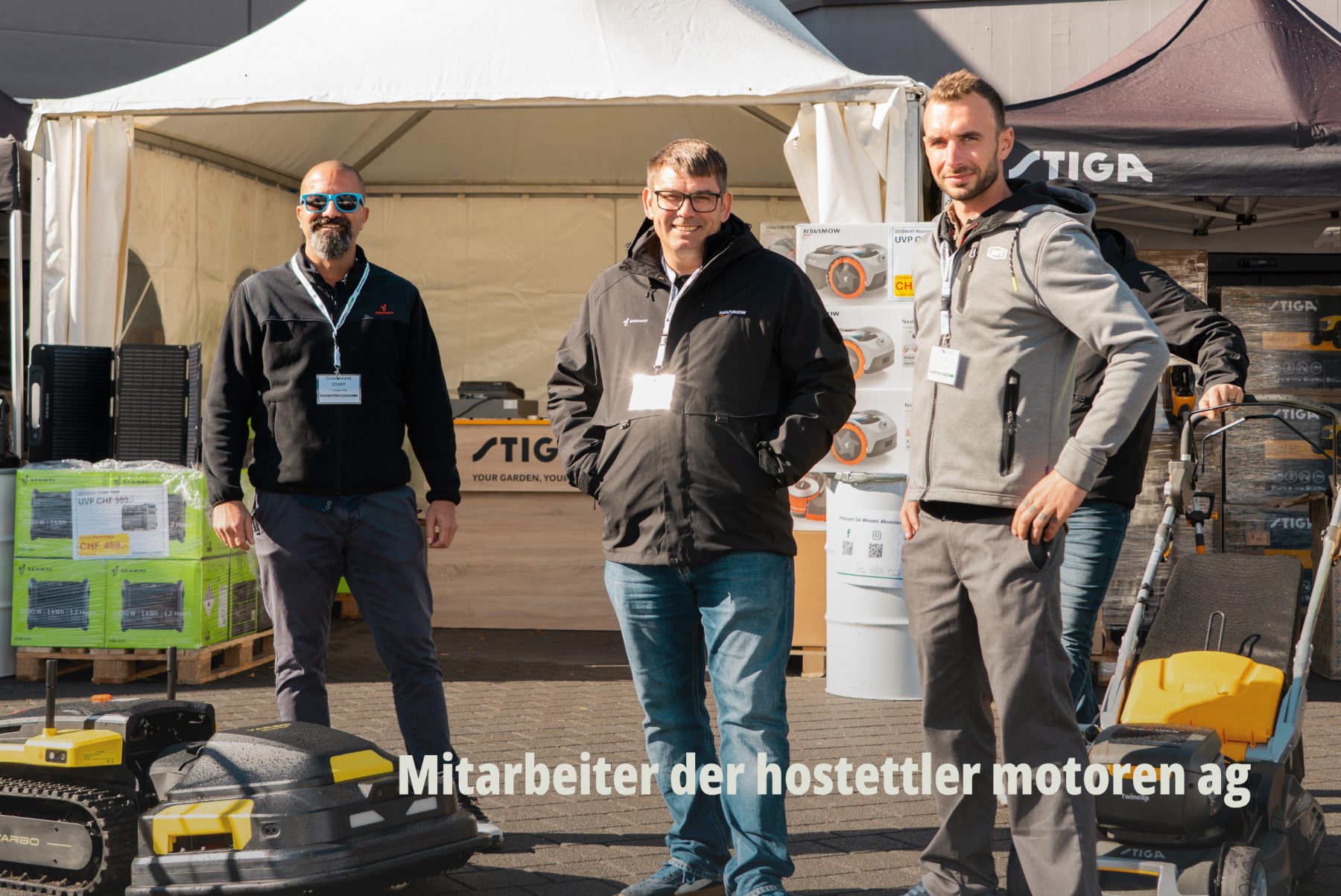 Teamfoto von drei Mitarbeitern der hostettler motoren ag vor einem Messestand - Eventfotografie von SR-STUDIOS. | SR-STUDIOS