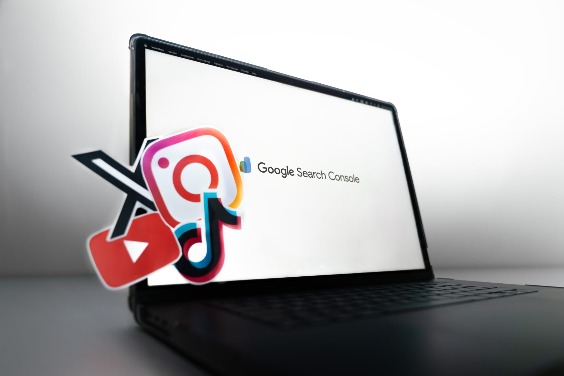 Laptop mit geöffneter Google Search Console auf dem Bildschirm. Davor schweben die Logos von Instagram, TikTok, YouTube und X als Symbol für die Integration von Social- und Videoplattformen in die Suchanalyse. | SR-STUDIOS