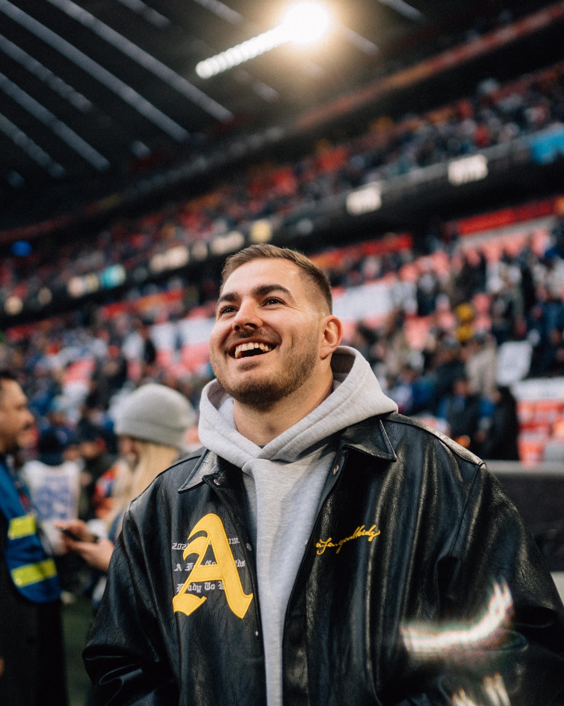 Creator July (@julyanpohl) steht lächelnd und in Bewegung im Freien in einem Fussballstadion. Das Bild findet man im Rahmen des Blogartikels von SR-STUDIOS zum Thema Community Management. | SR-STUDIOS