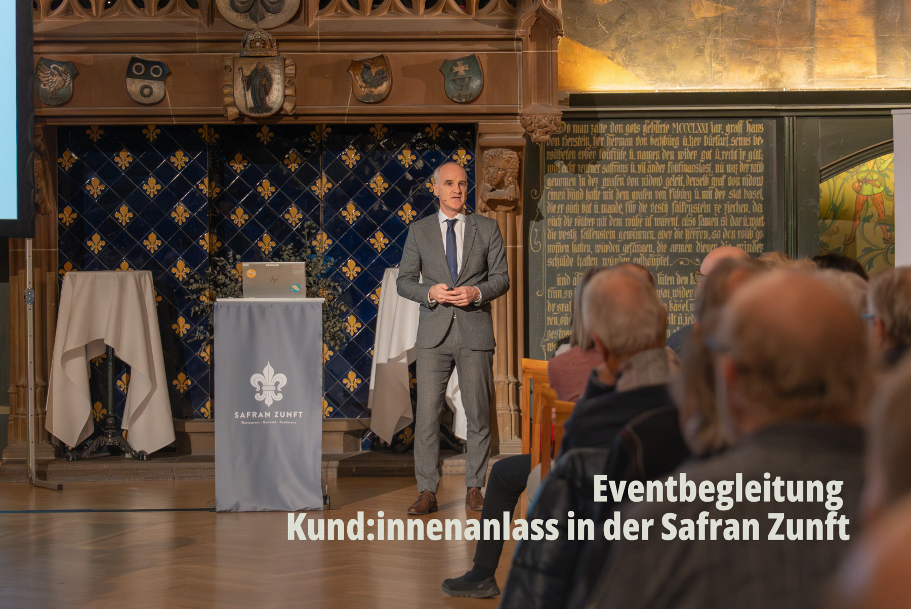 Referent in Anzug bei einem Fachvortrag vor historischer Kulisse; Professionelle Dokumentation von Firmenanlässen durch SR-STUDIOS für die Raiffeisenbank Basel. | SR-STUDIOS