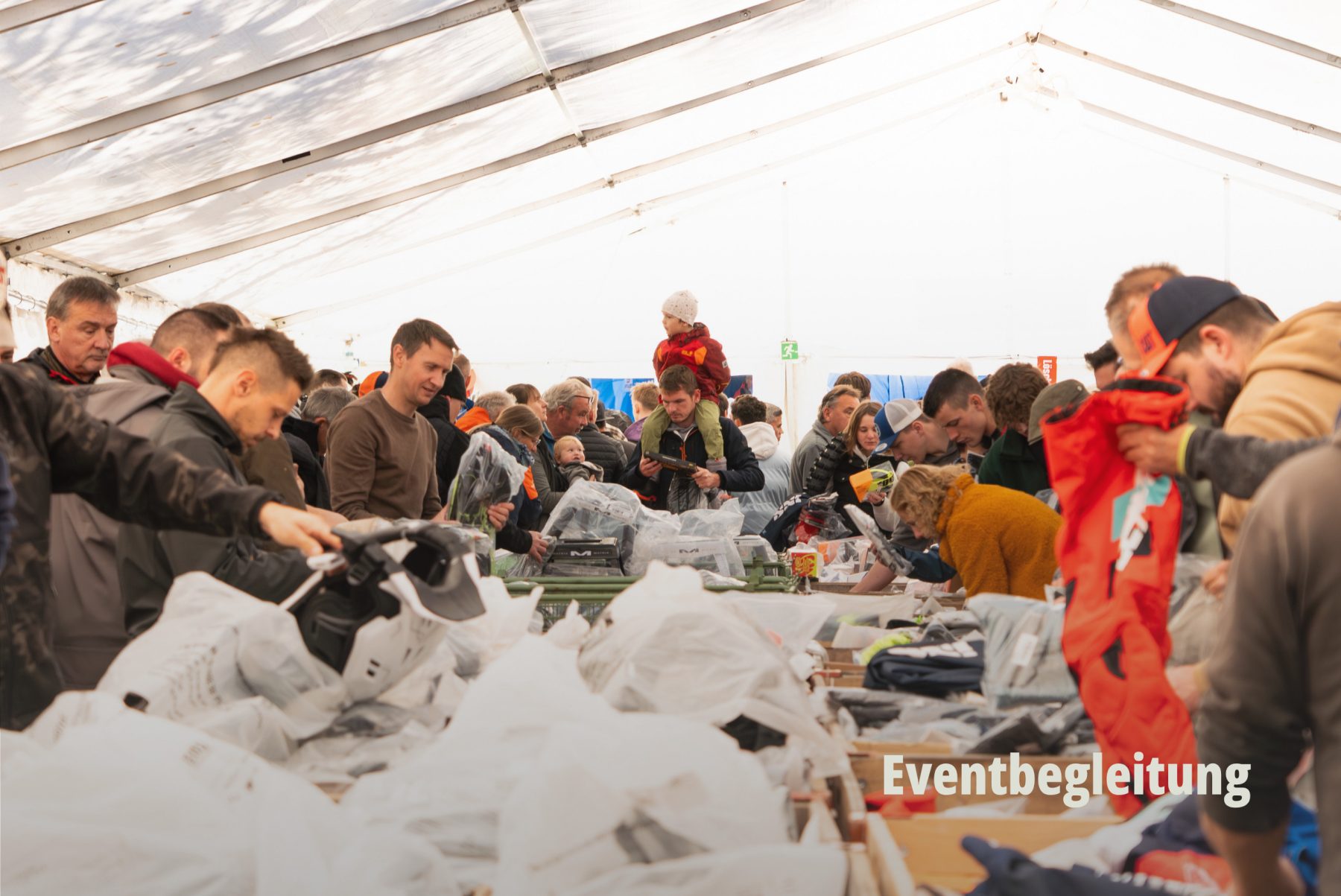 Impression der Eventbegleitung: Besucher an einem Wühltisch während einer Veranstaltung der hostettler motoren ag. | SR-STUDIOS