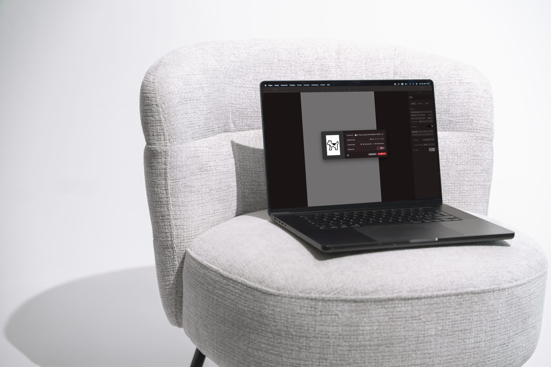 Ein dunkles MacBook steht auf einem hellgrauen, strukturierten Sessel. Auf dem Display des Laptops ist ein Systemeinstellungen-Fenster geöffnet, das ein kleines, einfaches, pixeliges Symbol eines Hundes (Clarus the Dogcow) zeigt, umgeben von einem weichen Schatten. Brand Maskottchen Chitchat von SR-STUDIOS. | SR-STUDIOS