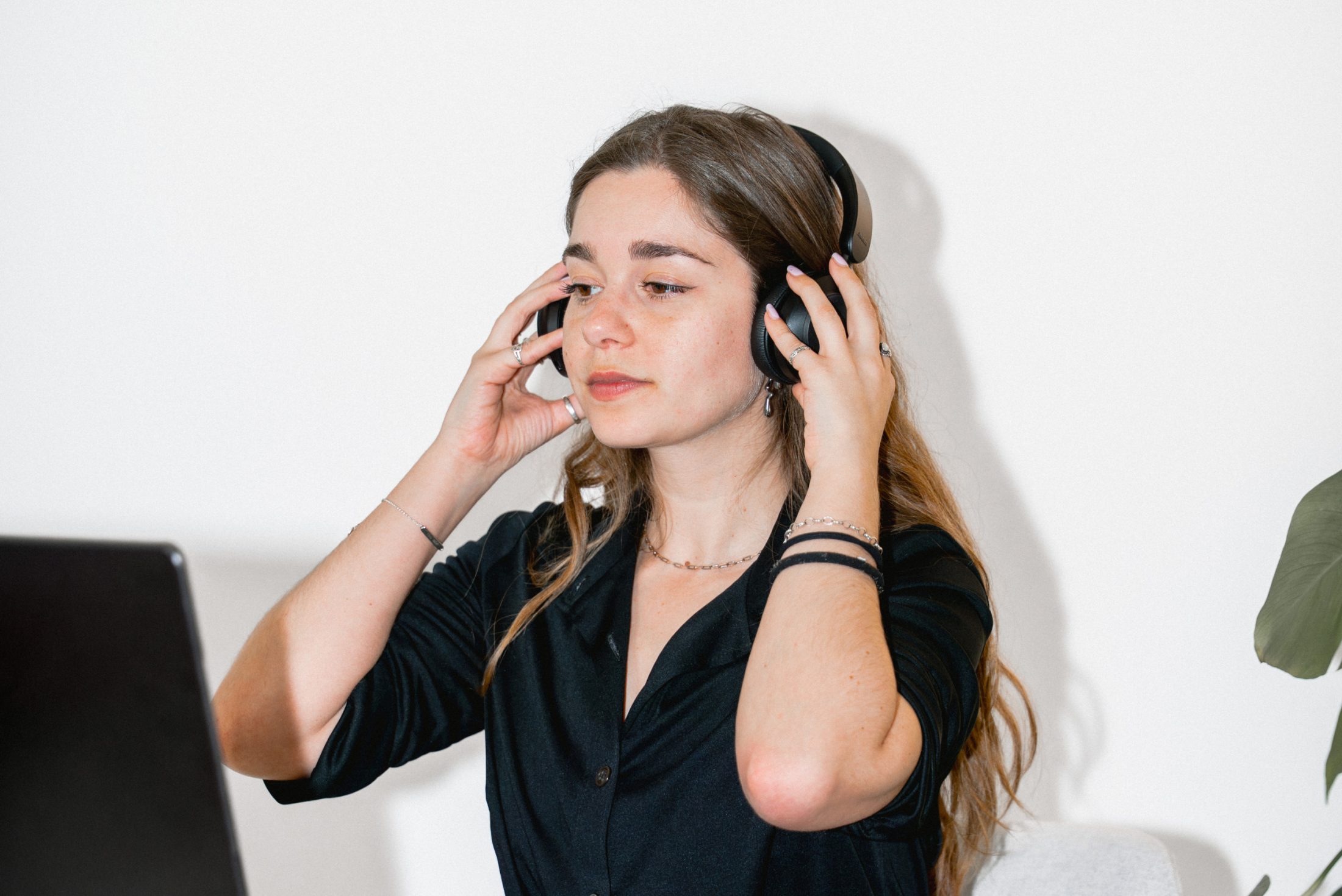 Lora Sibai, Social Media Specialist bei SR-STUDIOS, legt sich am Arbeitsplatz schwarze Over-Ear-Kopfhörer an, um sich konzentriert in ihre «Fokuszeit» zu begeben. Der Laptop ist teilweise links sichtbar. | SR-STUDIOS