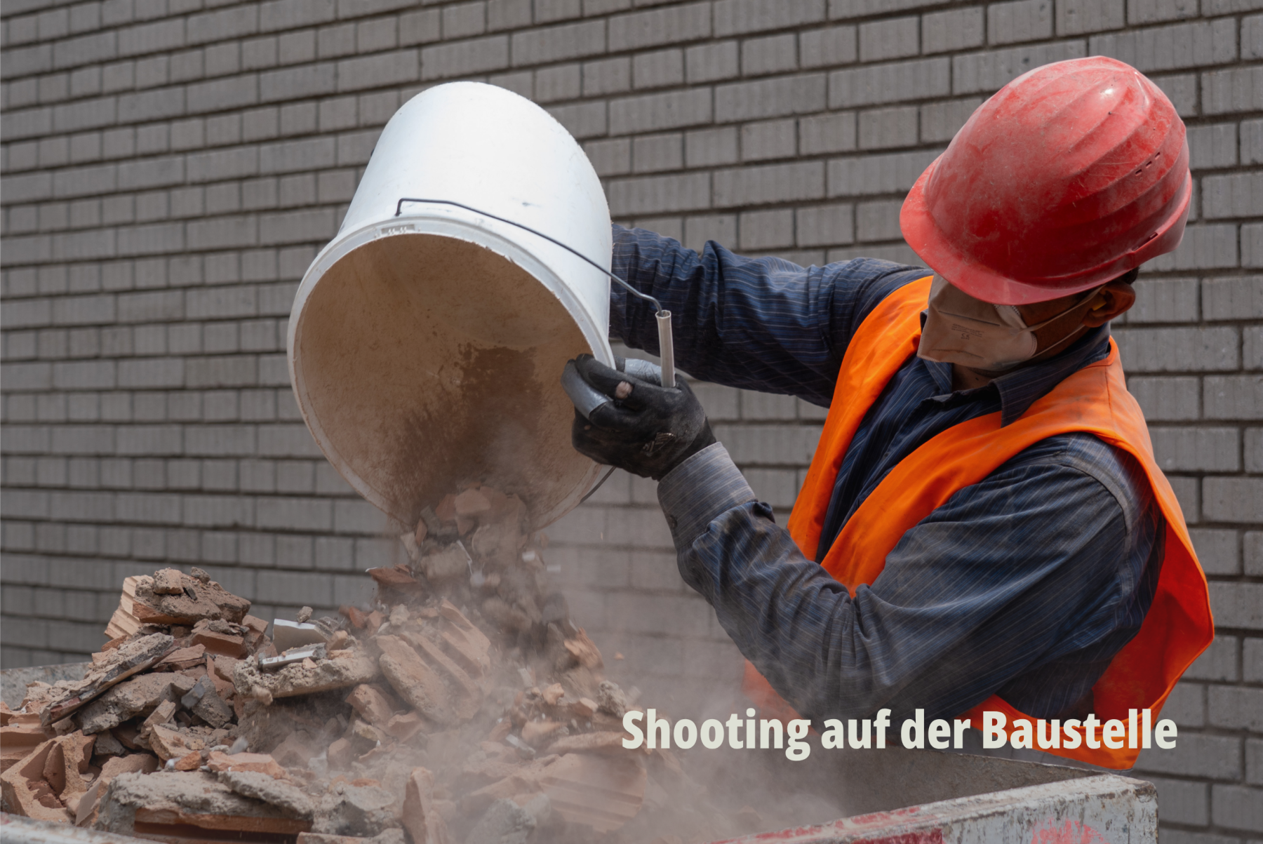 Dynamische Arbeitsaufnahme: Ein Bauarbeiter in Schutzkleidung leert Bauschutt aus einem Eimer in einen Container; Grollimund AG. | SR-STUDIOS