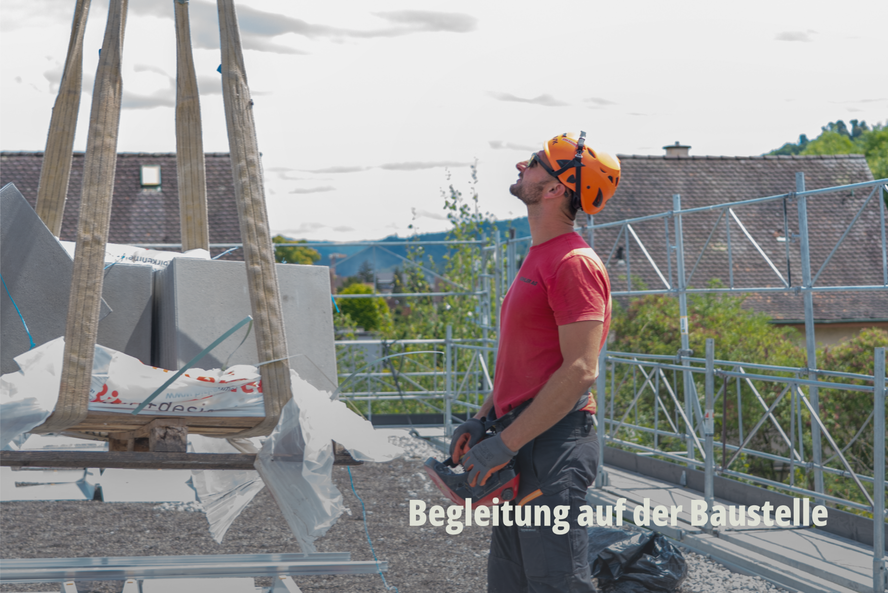 Baustellen-Dokumentation: Ein Bauarbeiter überwacht das Heben einer Last per Kran auf einem Gerüst unter blauem Himmel; Grollimund AG. | SR-STUDIOS