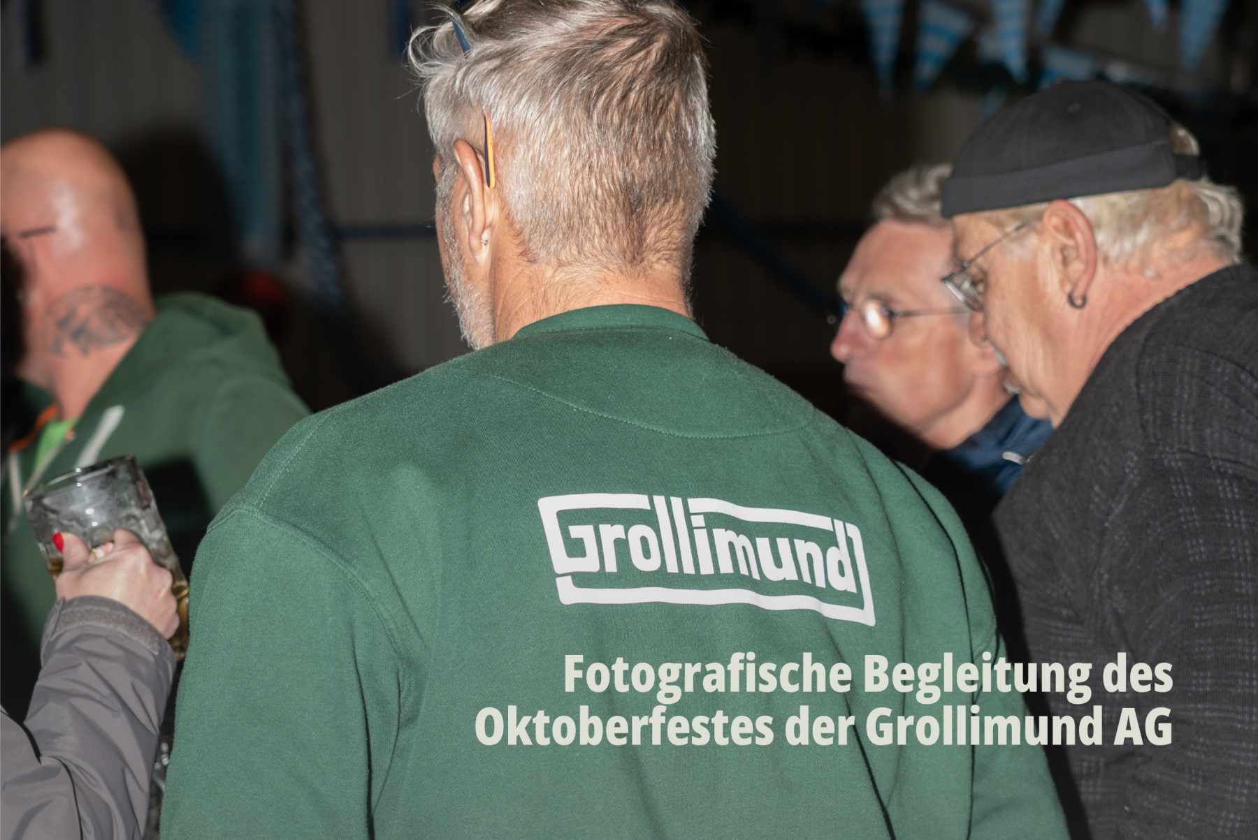 Fokus auf das Corporate Design: Rückenansicht eines Mitarbeiters mit dem Grollimund AG-Logo auf dem Pullover in einer Gruppe; Firmenevent; Oktoberfest. | SR-STUDIOS