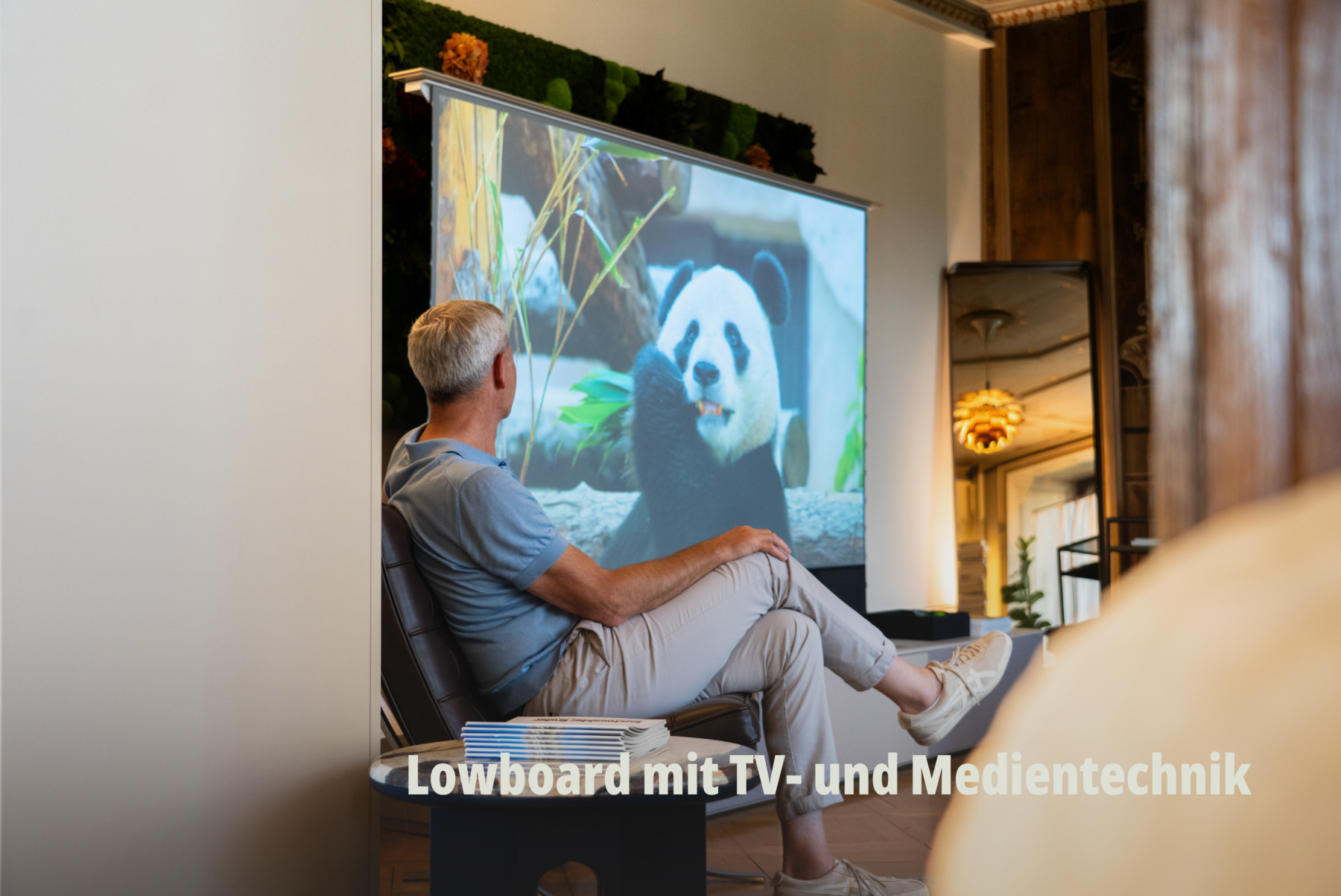 Lifestyle-Produktfotografie: Ein Mann nutzt ein Heimkino-System, das perfekt in eine massgeschneiderte Wohnwand integriert ist; vifian. | SR-STUDIOS