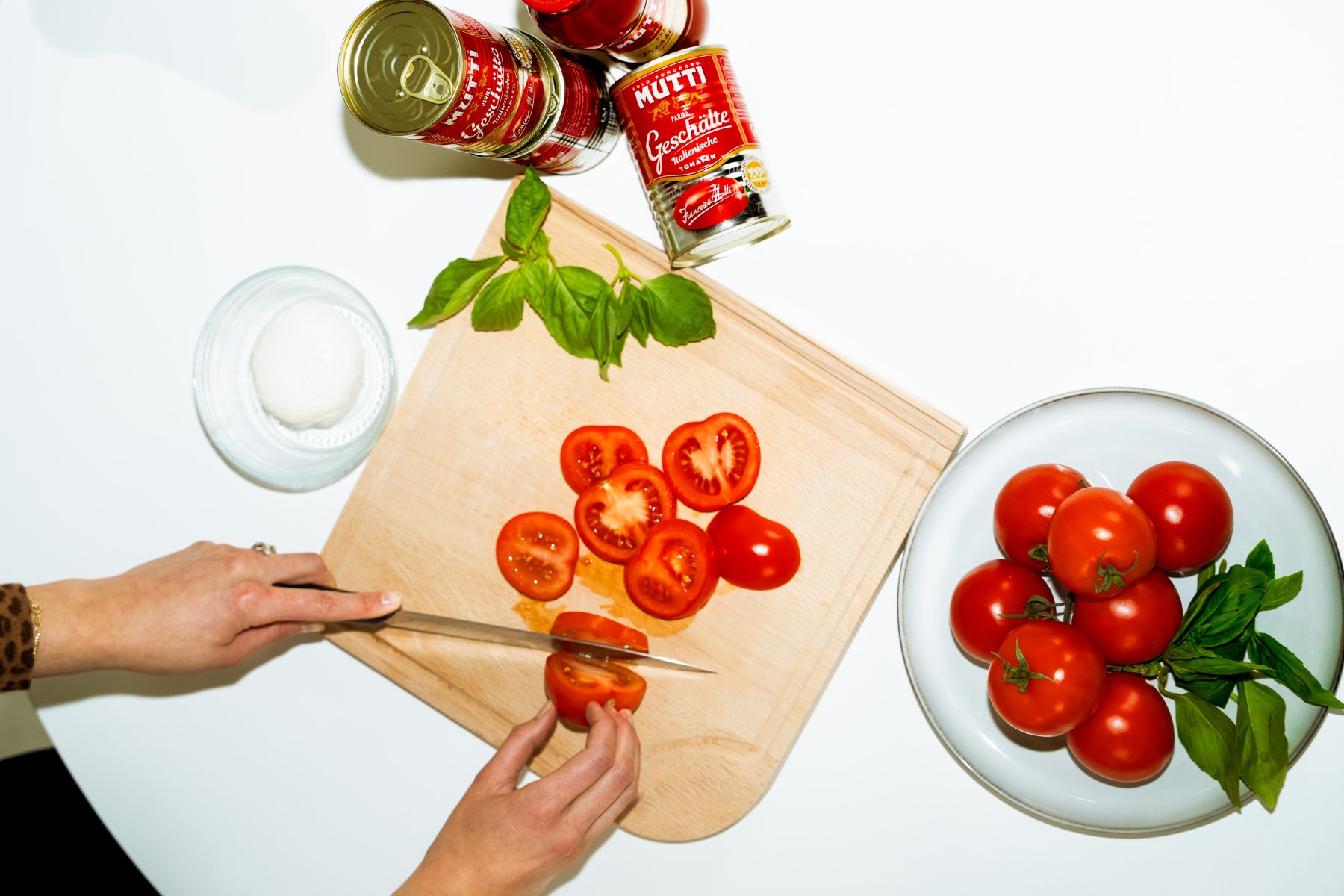 Authentisches Brand Storytelling: Zubereitung von Tomaten auf einem Holzbrett neben Mutti Tomatendosen für ein Brand Shooting. SR-STUDIOS. | SR-STUDIOS