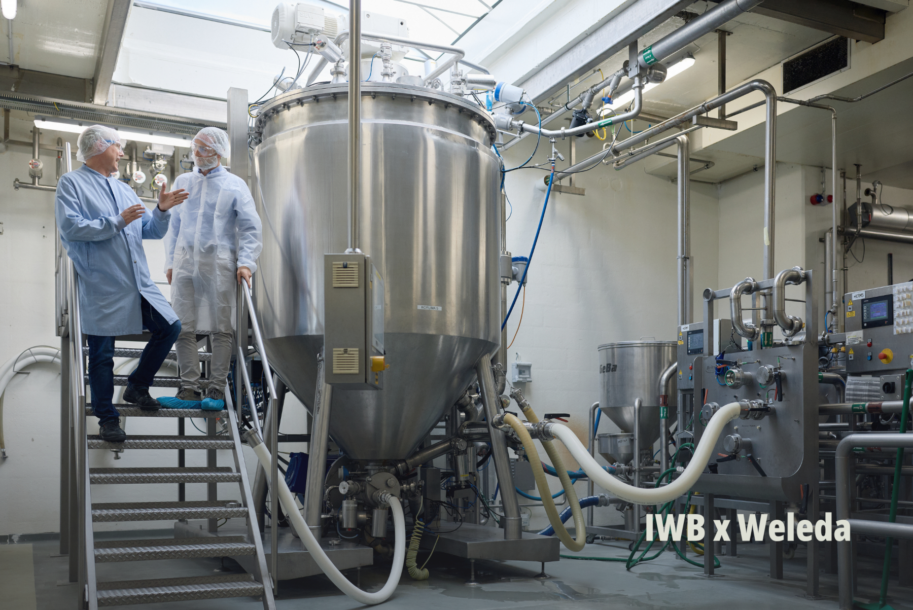 Blick in eine moderne Industrieanlage mit Fachpersonal in Schutzkleidung bei Besichtigung eines Projekts von IWB und Weleda. | SR-STUDIOS