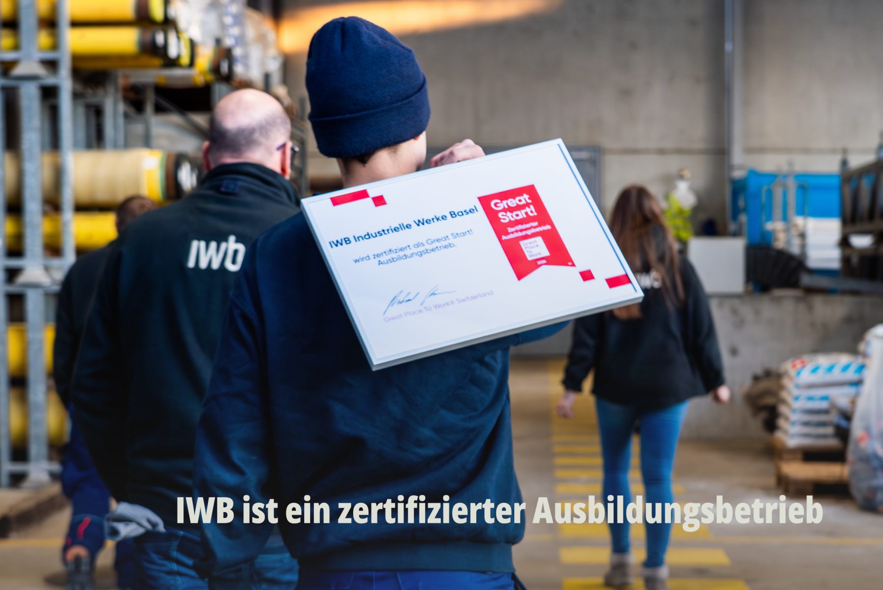 Rückansicht eines IWB Mitarbeiters in einem Logistikzentrum, der eine IWB Auszeichnung zum zertifizierter Great Start Ausbildungsbetrieb trägt. | SR-STUDIOS