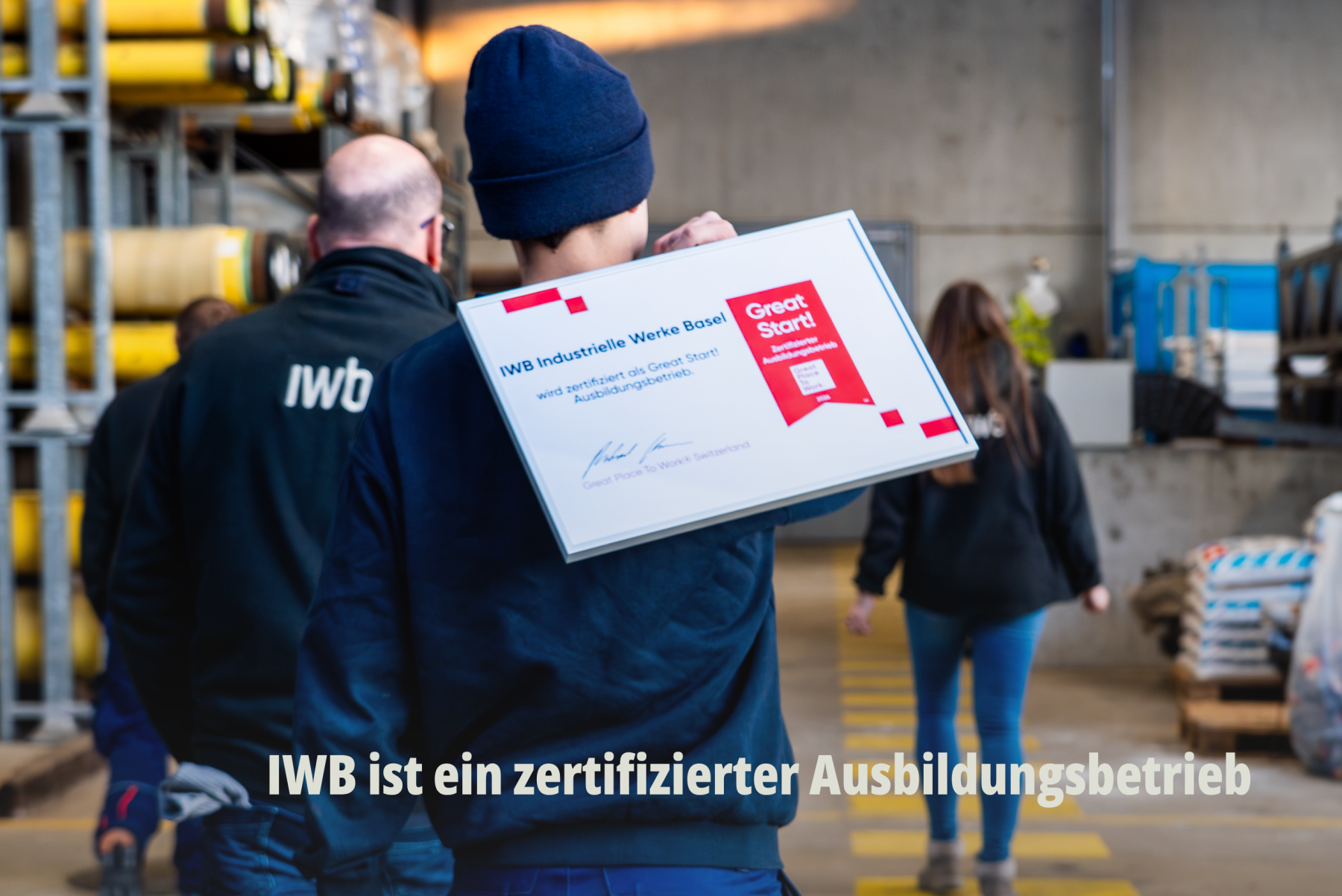 Rückansicht eines IWB Mitarbeiters in einem Logistikzentrum, der eine IWB Auszeichnung zum zertifizierter Great Start Ausbildungsbetrieb trägt. | SR-STUDIOS