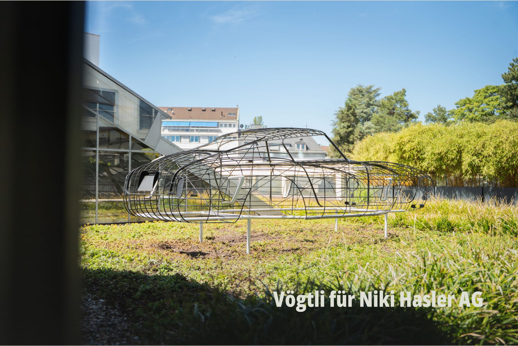 Drahtgitter-Skulptur in Form einer Silhouette eines Sportwagens (Ferrari) auf einem begrünten Flachdach. Vögtli Gartenbau GmbH für Niki Hasler AG fotografiert bei SR-STUDIOS. | SR-STUDIOS