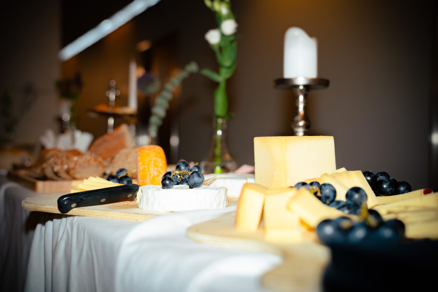 Ästhetisch angerichtete Käseplatte mit Trauben und Kerzenschein auf einem Holzbrett beim Event Embrace the Taste. Embrace the taste by SR-STUDIOS. | SR-STUDIOS
