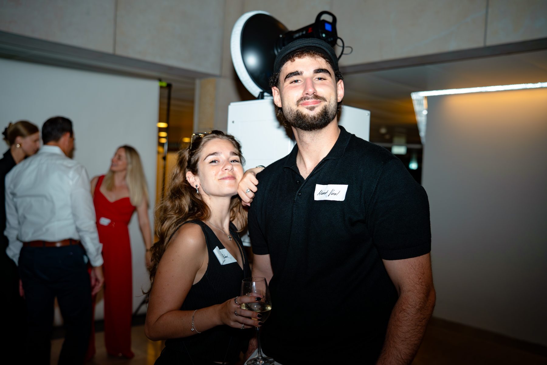 Eine Frau und ein Mann mit Namensschild lächeln auf dem Event Embrace the Taste. Mitarbeiter:innen bei Embrace the taste by SR-STUDIOS. | SR-STUDIOS