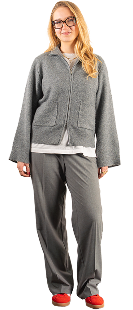 Social Media Marketing Spezialistin mit blonden Haaren trägt graues Casual-Outfit, enstpannt stehend mit lockerer Körperhaltung. | SR-STUDIOS