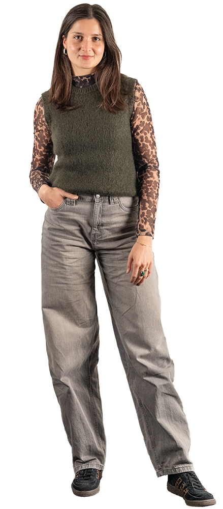 Interne Marketing-Mitarbeiterin mit braunen Haaren trägt grünes ärmelloses Oberteil, steht frontal für Corporate Branding. | SR-STUDIOS